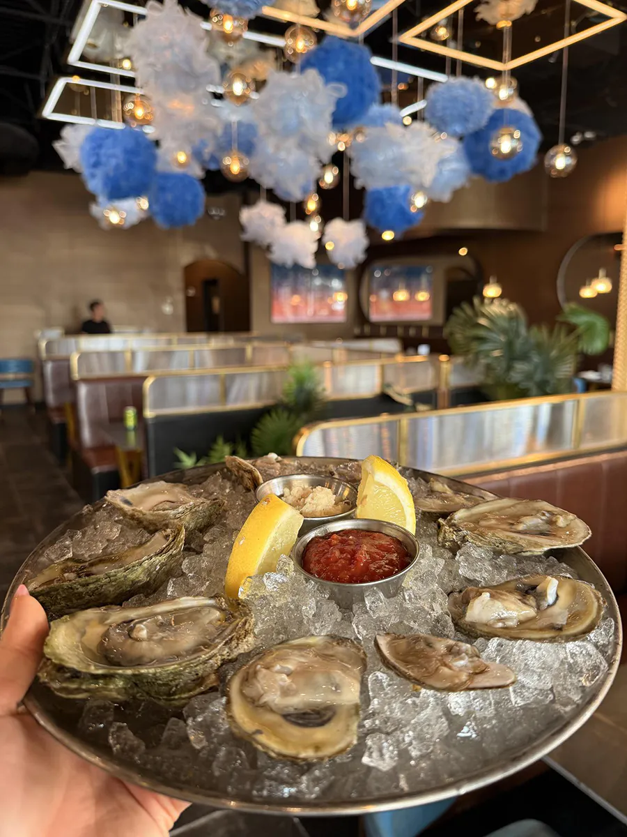 Fresh oysters on ice served with lemon and dipping sauces at 21 Raw Bar Taphouse & Grill, a Seafood Restaurant in Greenville