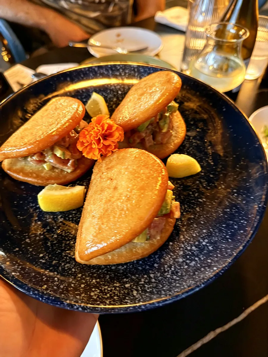 Crispy seafood sliders with avocado, lemon wedges and edible flower garnish at 21 Raw Bar Taphouse & Grill, a Seafood Restaurant in Greenville