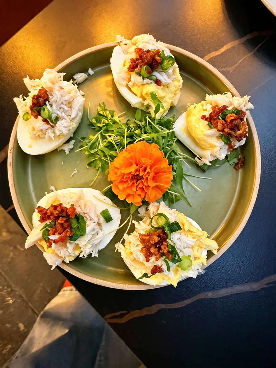 Crab-topped deviled eggs with bacon, green onions and fresh greens at 21 Raw Bar Taphouse & Grill, a Seafood Restaurant in Greenville