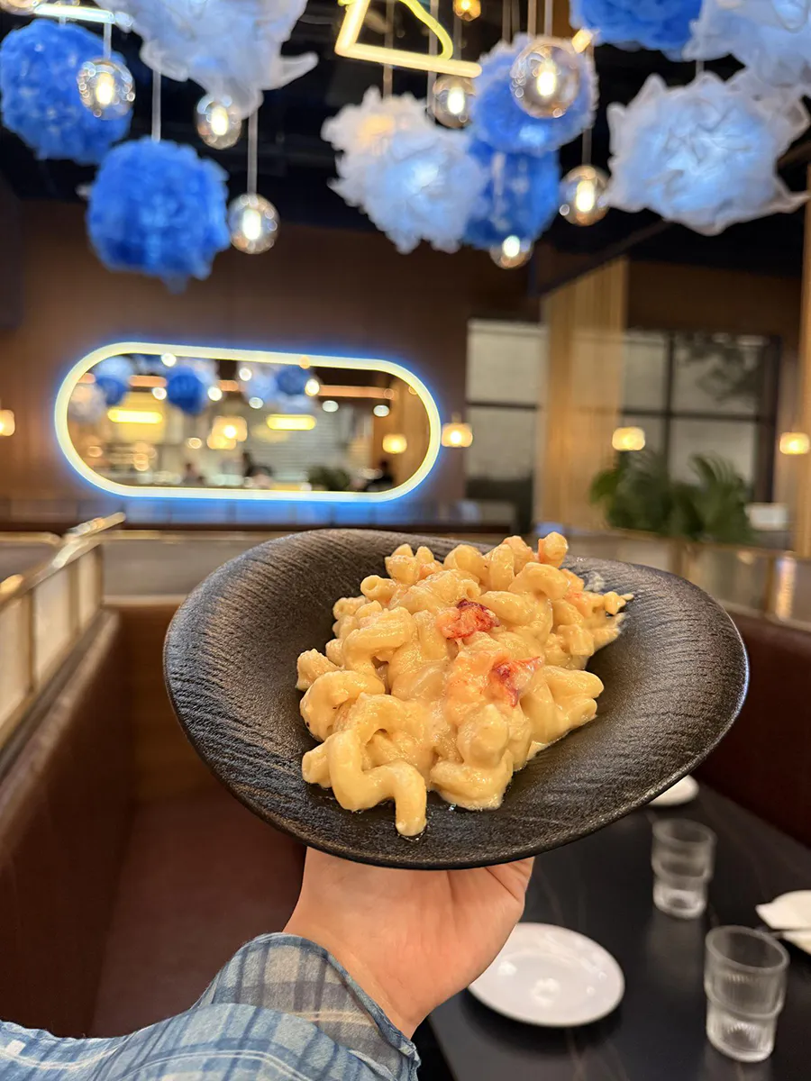 Creamy lobster mac and cheese served in a black bowl at 21 Raw Bar Taphouse & Grill, a Seafood Restaurant in Greenville